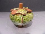 a green vase with a flower on it on a table