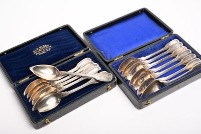 des cuillères en argent et des cuillères à soupe dans un étui posé sur une surface blanche