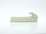 a white cat figurine sitting on top of a white plate