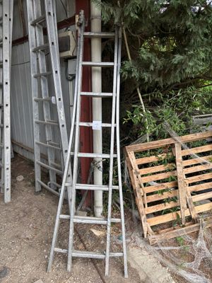 une échelle appuyée contre un immeuble, à côté d'une pile de palettes