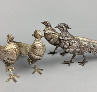 three silver metal birds are standing next to each other