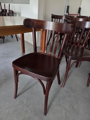 de nombreuses chaises en bois dans une pièce équipée d'une table et de chaises