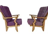 pair of purple upholstered chairs with wooden arms and legs