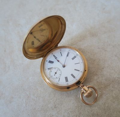 une montre de poche en or posée sur une surface blanche