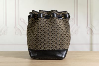 a brown and black bucket bag sitting on top of a wooden table