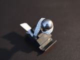 a black pearl and diamond ring on a black surface