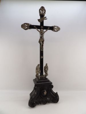 un crucifix ancien posé sur un socle, sur fond blanc