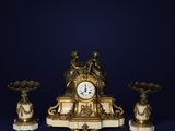 une horloge posée sur une table, à côté de trois vases