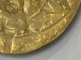 a gold medal with a picture of a man and a woman on it