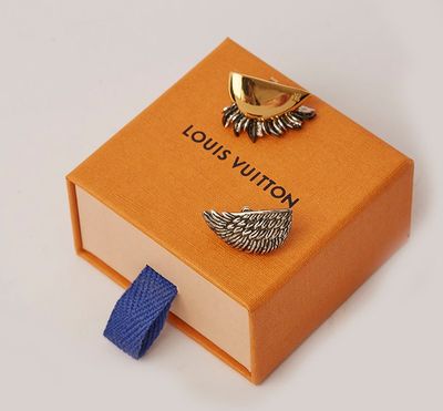 an orange box with a pair of earrings and a blue tie