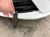 a person holding a ruler in front of a white car