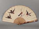 un éventail orné d'oiseaux, posé sur une table