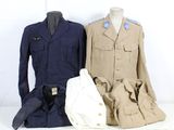 Trois uniformes militaires sont exposés sur une table, à côté d'un sac blanc