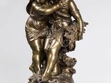 une statue antique en bronze représentant deux enfants enlacés, posée sur un socle en marbre