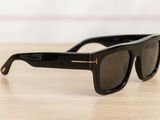black sunglasses on a wooden table with a white wall in the background