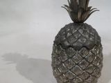 un ananas argenté posé sur une table blanche