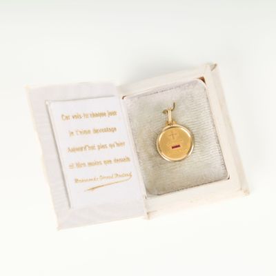 a small gold locke in a box on a white surface