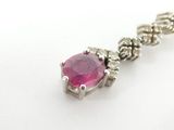 a close up of a necklace with a pink stone on a white surface