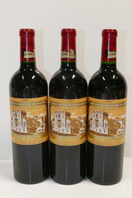 trois bouteilles de vin rouge sont alignées sur une surface blanche