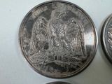 two silver coins sitting next to each other on a white surface