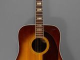 un gros plan d'une guitare acoustique sur fond gris
