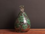 a glass bottle with a green and black design on it