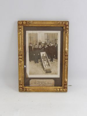 une vieille photo montrant un groupe d'hommes rassemblés autour d'un cercueil