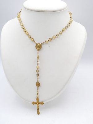 a close up of a necklace with a cross on a mannequin