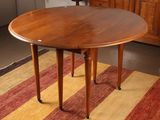 a round table with a wooden top on a striped rug