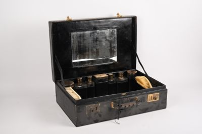une valise noire contenant un miroir, posée sur une surface blanche