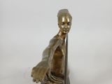bronze statue of a boy on a surfboard on a wooden base