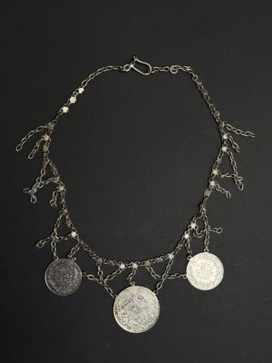 a close up of a necklace with coins on a black background