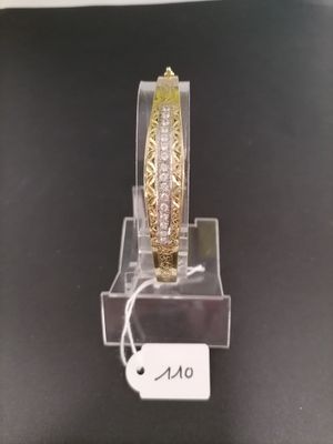 gold and diamond bangle bracelet on display on a clear acrylic stand