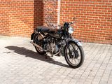 a black motorcycle parked on a brick sidewalk in front of a brick building