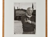 photographie en noir et blanc d'un vieil homme debout devant une maison