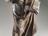 bronze statue of a woman holding a book with a chain around her neck