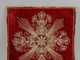 un gros plan sur un tissu rouge et doré orné d'une croix