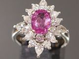 une photo d'une bague sertie d'un saphir rose et de diamants, posée sur un fond noir