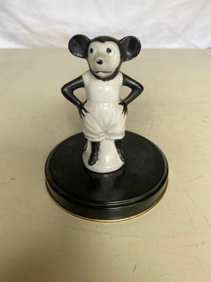 une figurine représentant une souris noire et blanche posée sur un socle noir