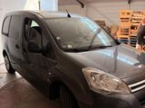 grey van parked in a garage with a man standing next to it