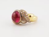 a gold ring with a red stone and diamonds