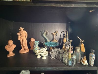 une étagère sur laquelle sont disposés de nombreux objets en verre et des vases
