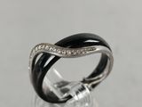 a close up of a black and white diamond ring on a clear glass