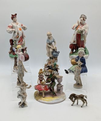 trois figurines représentant des personnes et un chien, posées sur une surface blanche