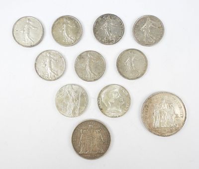 Plusieurs pièces de monnaie différentes sont disposées en triangle sur une surface blanche