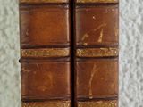 two old books sitting on top of a table next to each other