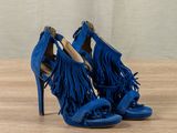 blue sued high heel sandals with fringes on a wooden surface