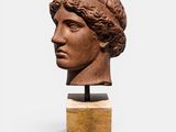 un gros plan sur une sculpture représentant une tête de femme posée sur un socle en bois