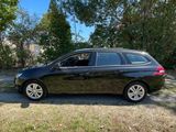 a black car parked in front of a house with trees in the background
