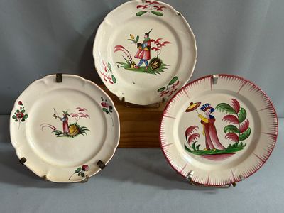 trois assiettes ornées de motifs sont posées sur un support en bois